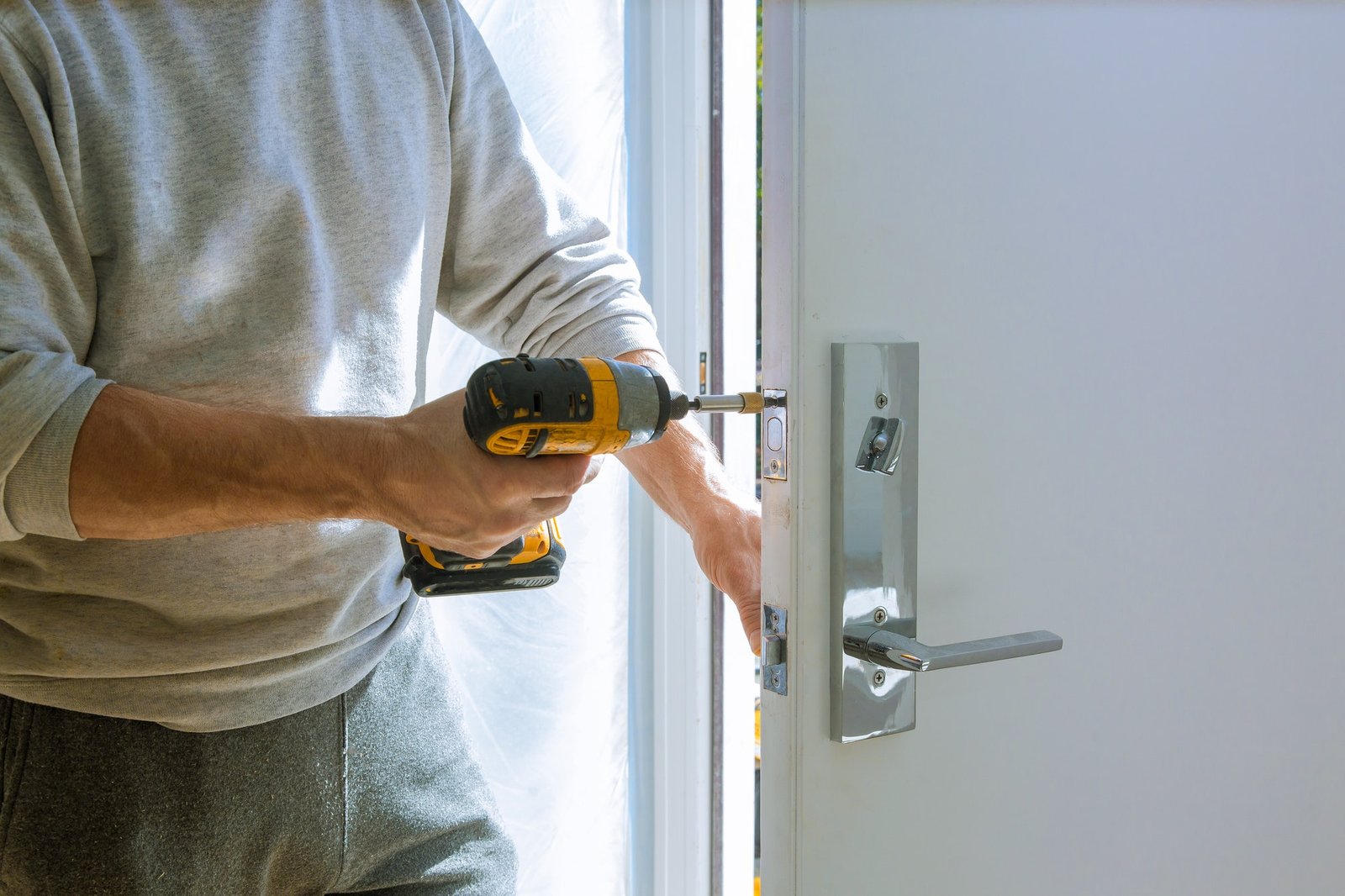 Installation with a lock in the door leaf using an drill screwdriver close-up.